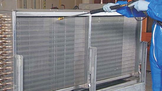 Professional HVAC coil cleaning agent spraying down a coil refrigeration system.