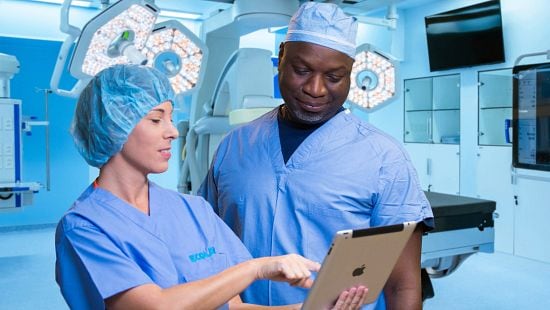 doctor and nurse view information on a tablet in operating room