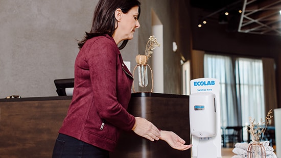 Woman using a touchless Nexa hand sanitizer station