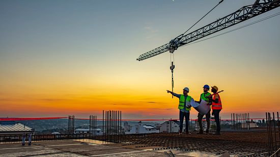 Three engineers at a construction site during sunset